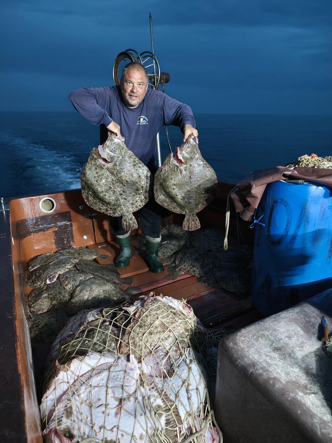 Калкан - мъж държи две огромни риби калкан