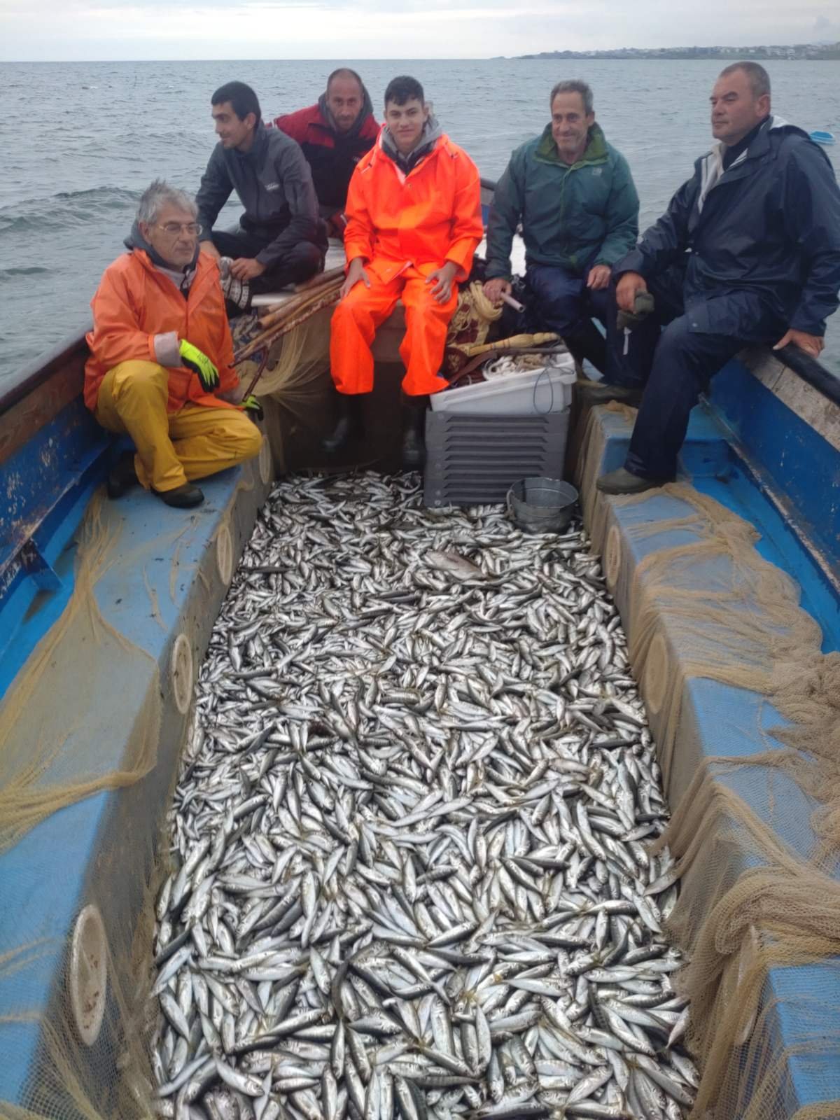 Шест рибари с лодка пълна с цаца